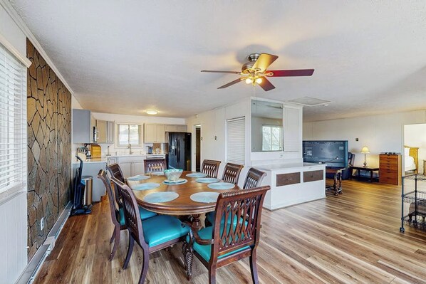 A dining area with a round table, chairs, and a ceiling fan.