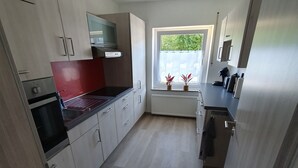 Cozinha moderna com armários de madeira clara, bancada preta e janela com plantas.