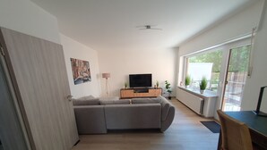 Uma sala de estar moderna com um sofá seccional, uma TV de tela plana e um espaço de jantar com mesa e cadeiras.