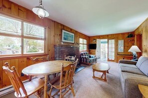 A wooden interior with a dining table, chairs, a sofa, and a fireplace. - 4BR home with grill, close to town & lake (Queensbury)