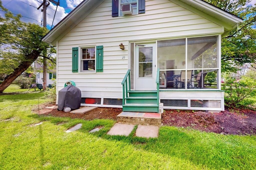 A single-story house with a front porch, a covered grill, and a number 29 on the door.