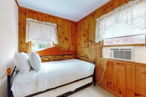 A single bed with a headboard, two pillows, and a window with a white curtain. - 4BR home with grill, close to town & lake (Queensbury)