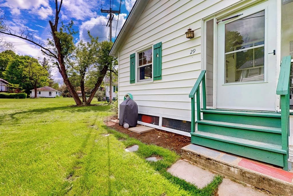 A house with a green front porch, a number '29' on the door, and a lawn with a tree.