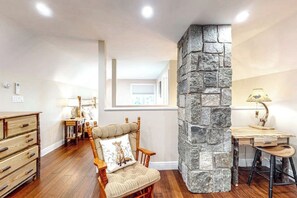 Une pièce avec un mur d’accent en pierre, des meubles en bois et une fenêtre laissant entrer la lumière naturelle.