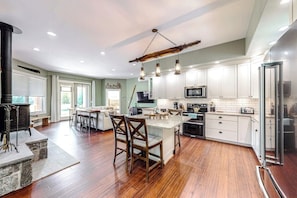 A modern kitchen with white cabinets, a central island, and a hanging light fixture. - 3 BR riverfront house with wood stove - near skiing (North Creek)