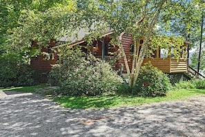 A wooden cabin with a porch, surrounded by dense greenery. - Beautiful 5BR Lakefront Adirondacks - Dock (Chestertown)