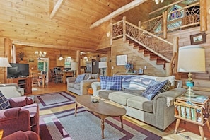 A wooden interior with a staircase, a sofa, a coffee table, and a television. - Beautiful 5BR Lakefront Adirondacks - Dock (Chestertown)