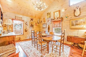 A wooden interior with a dining table, chairs, a chandelier, and various wall decorations. - Dog-friendly 2BR cabin with mountain view (Indian Lake)