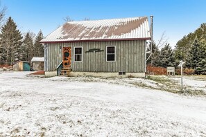 A small, single-story building with a metal roof and a wooden door. - Dog-friendly 2BR cabin with mountain view (Indian Lake)