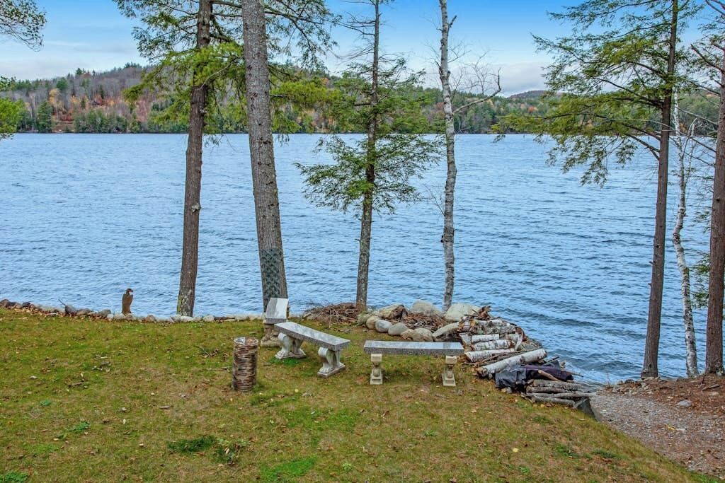 A lakeside setting with a bench and a stone fireplace.