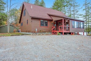 Une cabane en bois à deux étages, avec un toit rouge et une véranda couverte.