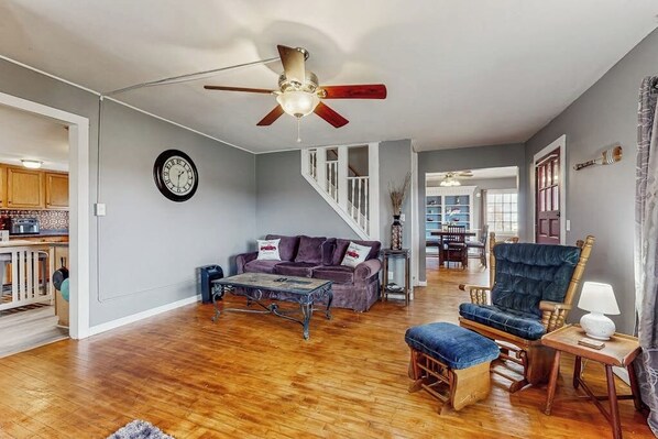 A spacious living room with a ceiling fan, a sofa set, a coffee table, and a wooden rocking chair.