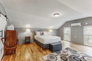 A bedroom with a bed, bedside tables, a chair, a rug, and a window.
