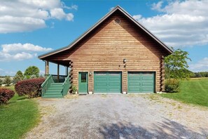 A wooden building with a gabled roof, a covered porch, and two green garage doors. - 3BR cabin home withlake views, soaking tub - dogs ok (Dundee)