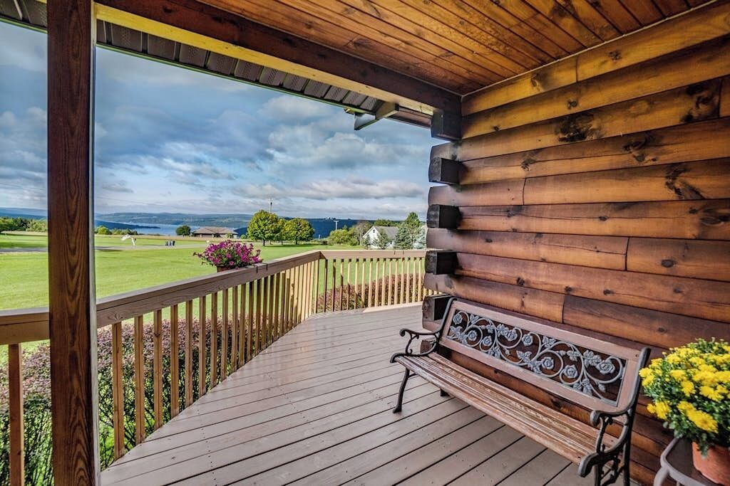 Una terraza de madera con un banco y barandilla, con vistas a un paisaje verde.