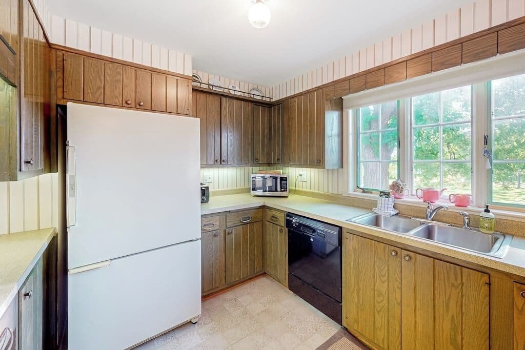 A kitchen with wooden cabinets, a white refrigerator, a microwave, and a dishwasher.