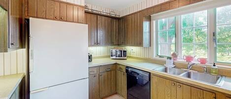 Une cuisine avec des meubles en bois, un réfrigérateur blanc, un four à micro-ondes et un lave-vaisselle.