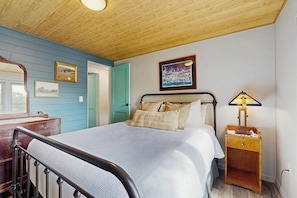 Un dormitorio con cama, mesita de noche, lámpara y puerta.