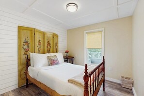 Un dormitorio con cama de madera, ventana con vistas y una lámpara en el techo.