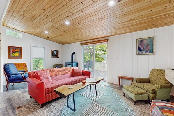 Ein Wohnzimmer mit einem roten Sofa, einem Holztisch und gemusterten Teppichen.