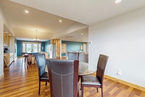 A spacious dining area with a round table and four chairs, a kitchen with wooden cabinets, and a large window providing natural light. - 1BR home w/deck, countryside views & close to town (Penn Yan)