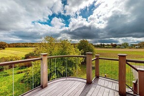 A wooden deck with a railing overlooking a green landscape and a cloudy sky. - 1BR home w/deck, countryside views & close to town (Penn Yan)