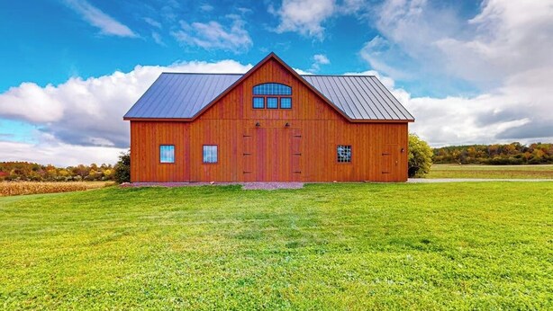 A large wooden barn with a metal roof, a central door, and two windows on the side. - 1BR home w/deck, countryside views & close to town (Penn Yan)