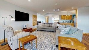 A spacious living area with a sofa, coffee table, and a flat-screen TV mounted on the wall. - 1BR home w/deck, countryside views & close to town (Penn Yan)
