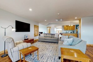 A spacious living area with a sofa, coffee table, and a flat-screen TV mounted on the wall. - 1BR home w/deck, countryside views & close to town (Penn Yan)