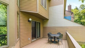 Un balcon avec une table et des chaises, une porte coulissante et une fenêtre.