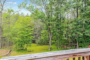 A wooden deck overlooking a forested area with dense greenery and trees.