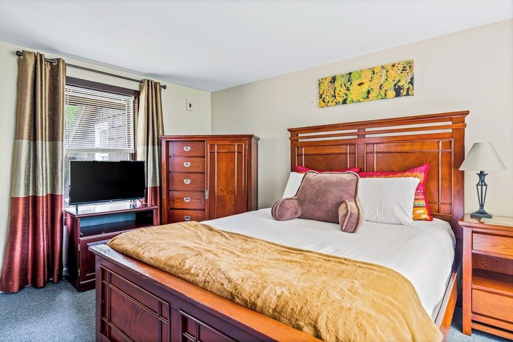 A hotel room with a bed, a television, a desk, and a nightstand.