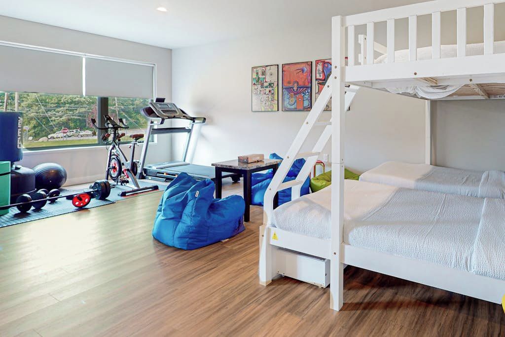 Une chambre avec un lit superposé, du matériel de sport et une fenêtre donnant sur un beau paysage.