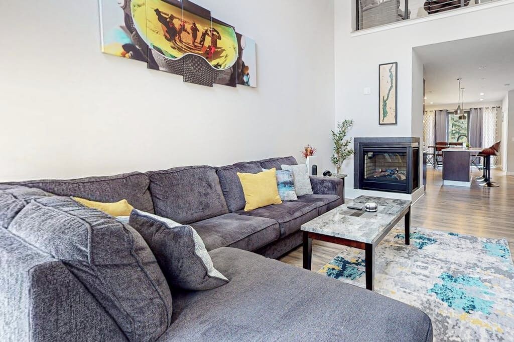 A modern living room with a sectional sofa, a flat-screen TV, and a fireplace.