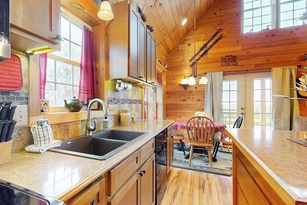 A kitchen with wooden cabinets, a sink, and a dining area with a chair.