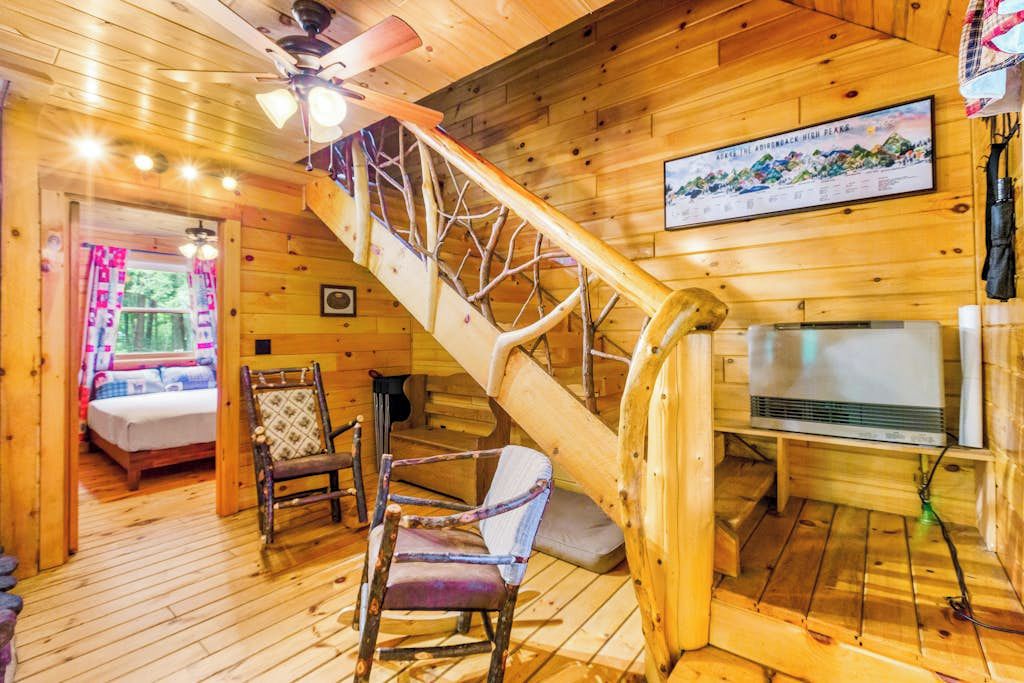 Ein Holzinnenraum mit Treppe, einem Bett, einem Sessel und einem Fernseher.