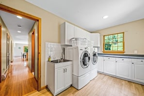A laundry room with a washing machine, a sink, and a window with a view of greenery. - Quiet 4BR Adirondacks Dog Friendly - Hot Tub (Johnsburg)