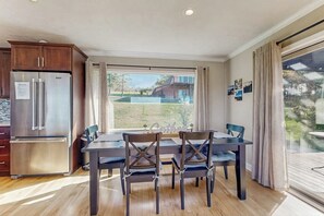 Ein Essbereich mit Tisch und Stühlen, einem Kühlschrank und Blick ins Freie.