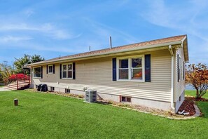 Ein bungalowartige Haus mit Veranda, einer kleinen angeschlossenen Garage und einem gepflegten Rasen.