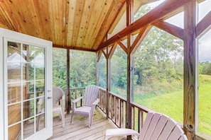 A wooden deck with two Adirondack chairs, a glass door, and a view of a green landscape. - 1BR dog-friendly house close to Seneca Lake (Hector)