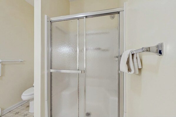 Un baño con cabina de ducha de vidrio, un inodoro y un perchero para toallas.