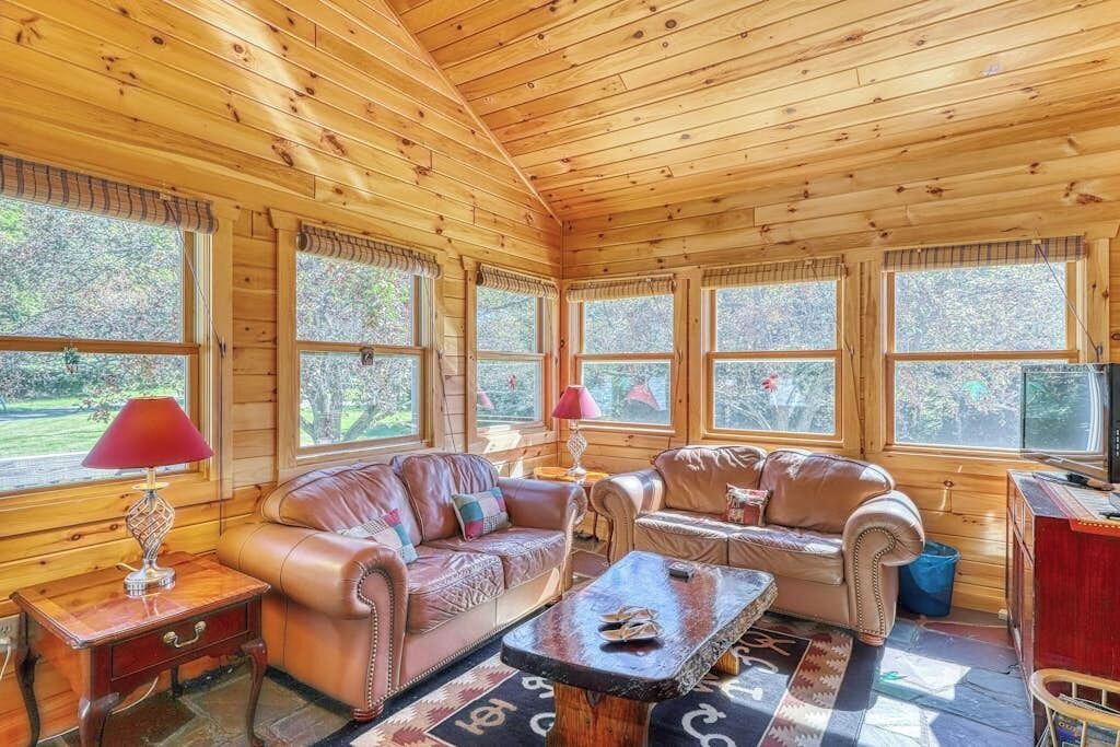 A log cabin interior with two leather sofas, a coffee table, and a television.