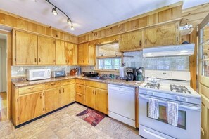 A kitchen with wooden cabinets, a microwave, a stove, and a dishwasher. - 4BR Lakefront Adirondacks - Dock (Brant Lake)