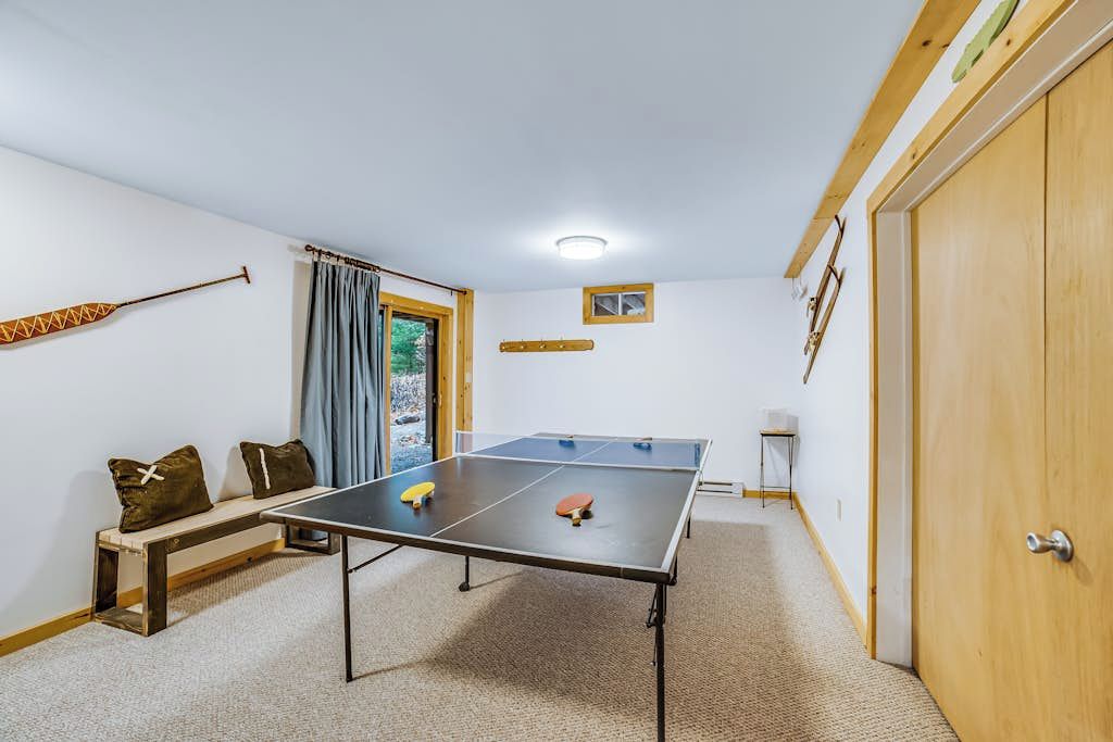 A room with a ping pong table, a bench, a door, and a small window. - Child-friendly 3BR Adirondacks - Fireplace (Warrensburg)
