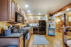 A kitchen with wooden cabinets, a stove, a refrigerator, and a blue side table. - Child-friendly 3BR Adirondacks - Fireplace (Warrensburg)