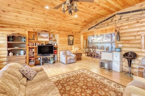 Ein Holzblockhaus-Interieur mit Fernseher, einer Sitzecke und einem Essbereich.