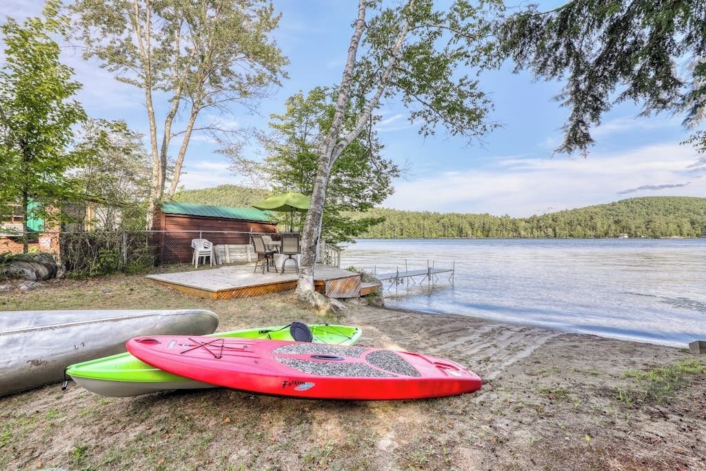 A lakeside cabin with kayaks and a deck overlooking the water.