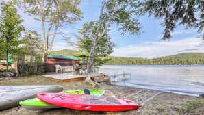 Eine Ferienhütte am See mit Kajaks und einer Terrasse mit Blick auf das Wasser.