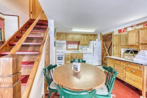 A kitchen with wooden cabinets, a dining table with chairs, and a staircase. - Beautiful 1BR Lakefront Adirondacks - Dock (Chestertown)