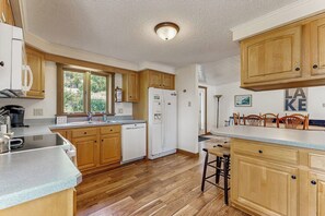 A kitchen with wooden cabinets, a dishwasher, and a refrigerator. - Lakefront Retreat w/Private Dock & Cozy Deck Views (Penn Yan)